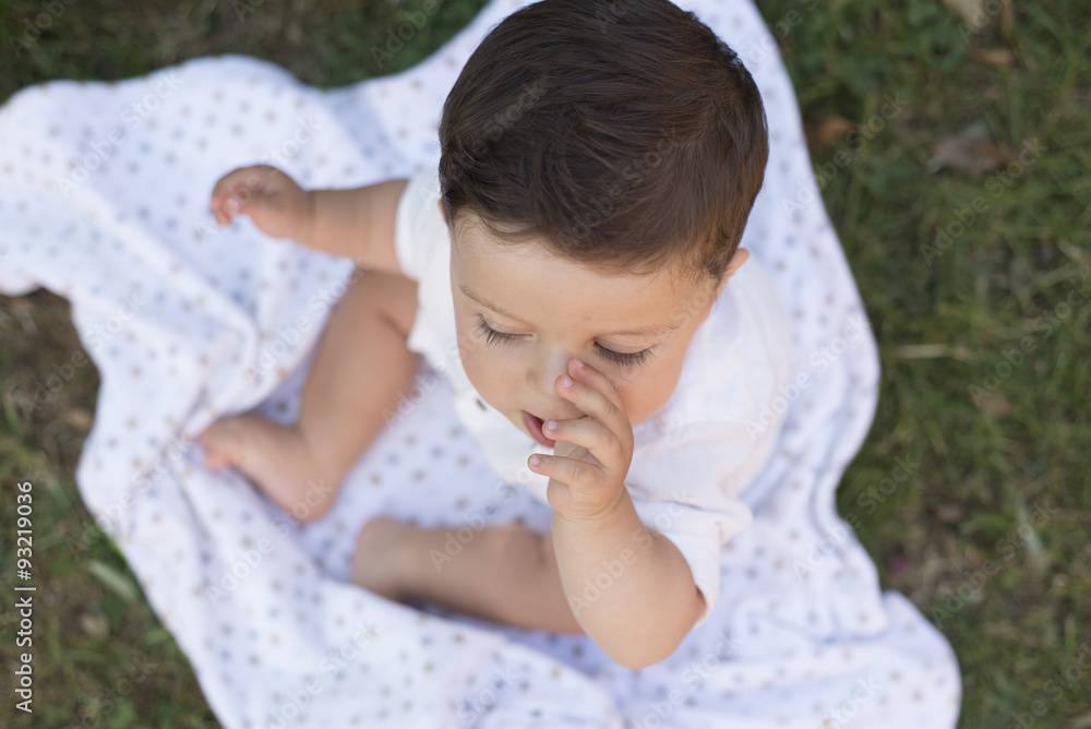 Baby boy sitting on a blanket sucking his thumb Baby boy sitting on a blanket sucking his thumb
