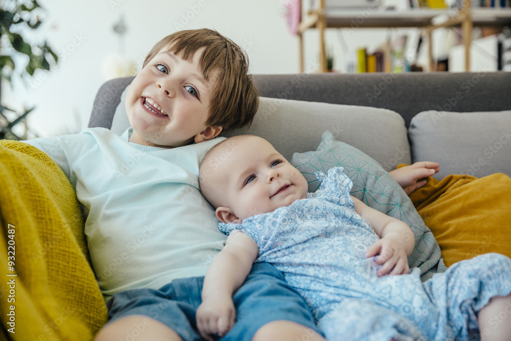 Smiling baby girl and brother on couch Smiling baby girl and brother on couch