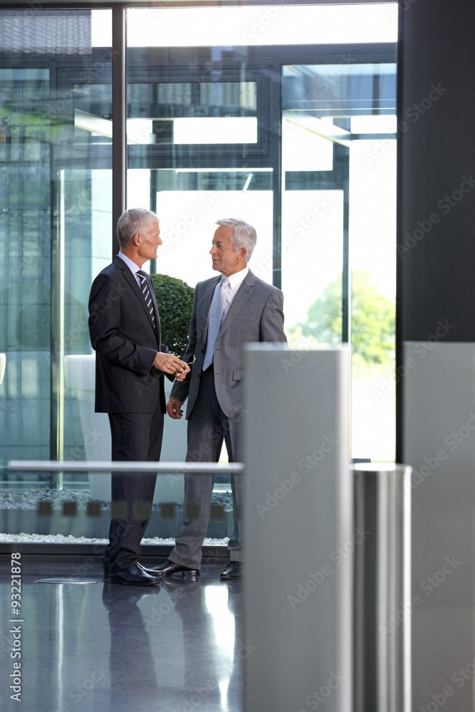 Two businessmen talking in office lobby Two businessmen talking in office lobby