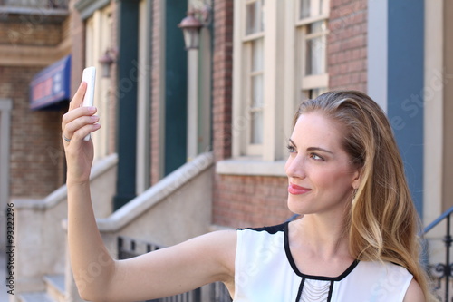 Pretty blonde with long hair takes selfies with her smartphone 