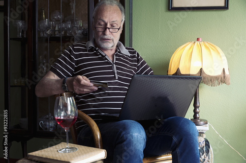 Senior man with laptop and credit card at home photo