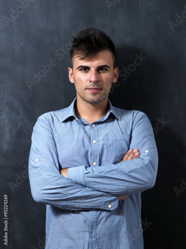 Portrait of a serious young man standing against chalkboard