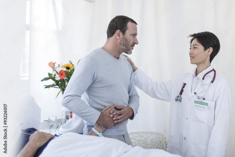 Doctor consoling man visiting patient in hospital Doctor consoling man visiting patient in hospital