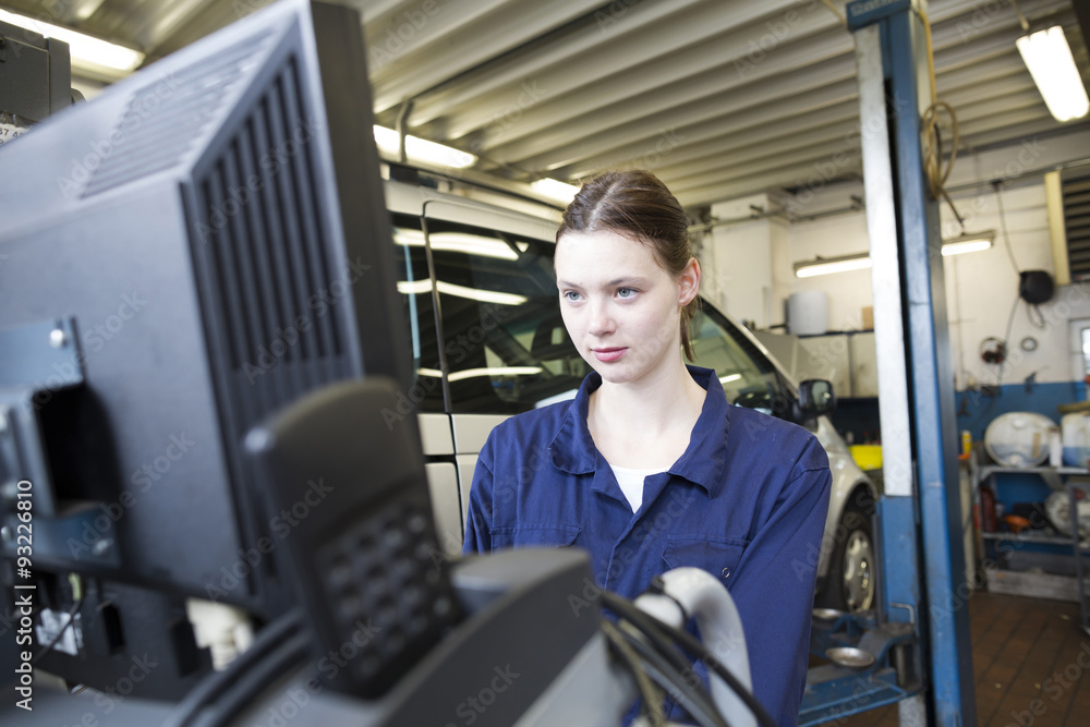 Young woman in repair garage checking car with electronic control Young woman in repair garage checking car with electronic control