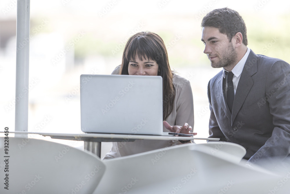 Two business people with laptop sitting on a terrace Two business people with laptop sitting on a terrace