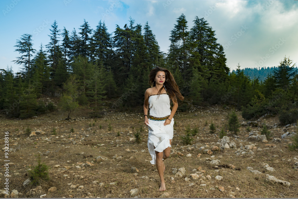 Naklejka premium girl in a beautiful dress running at the forest