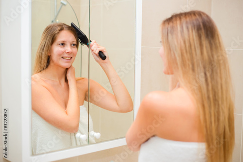 young woman looking in the mirror brushing her hair