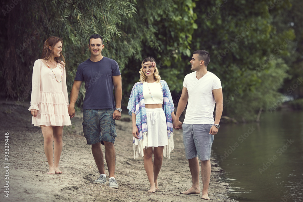 Two young couples walking in nature along the river Two young couples walking in nature along the river