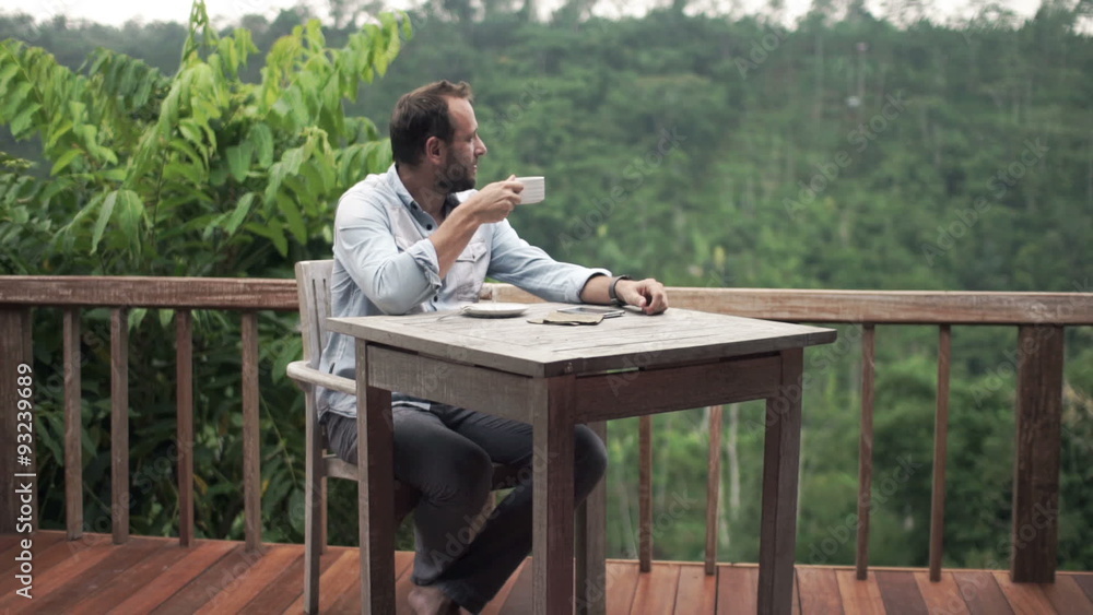 Young, happy man relaxing and drinking coffee by table on terrace
Young, happy man relaxing and drinking coffee by table on terrace