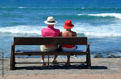 Senior couple sitting on a bench by the ocean. © svf74