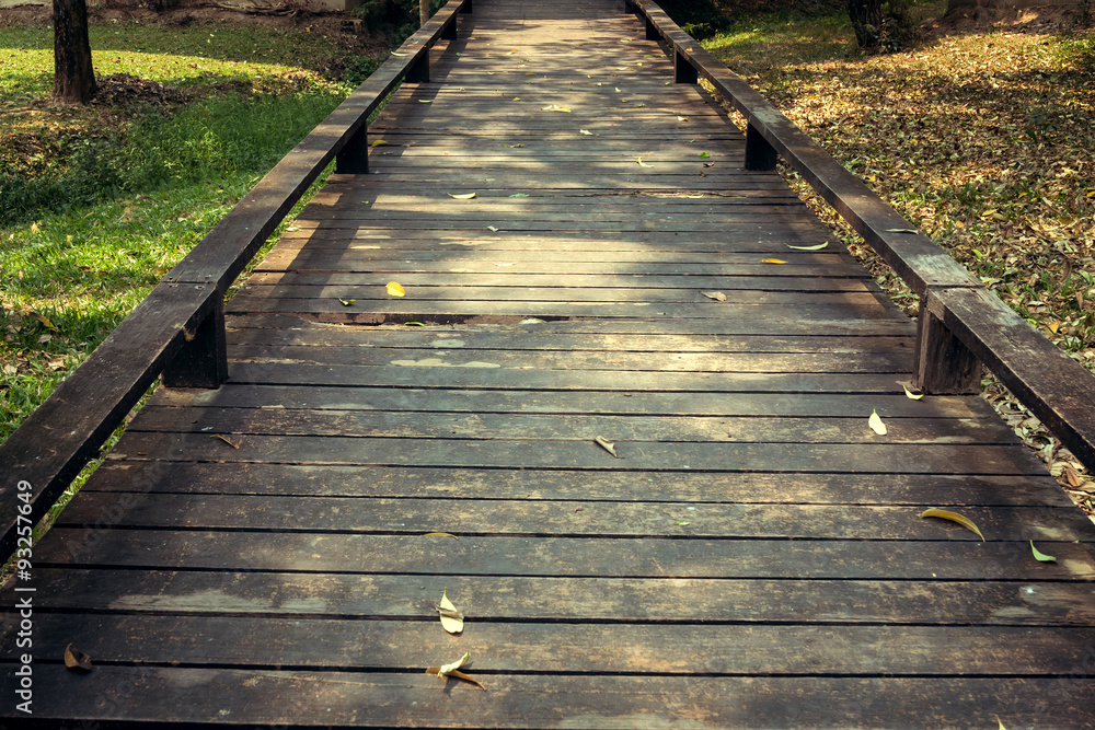 old wooden walkway with falling leaves in the morning of autumn old wooden walkway with falling leaves in the morning of autumn