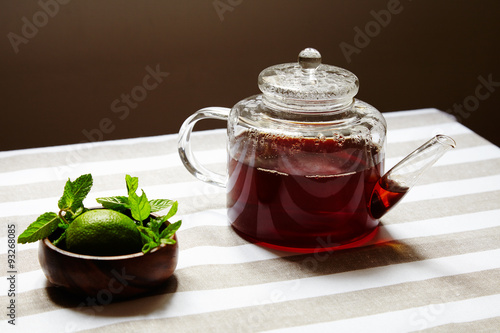 Tea in transparent teapot and wooden box with lime and mint leav