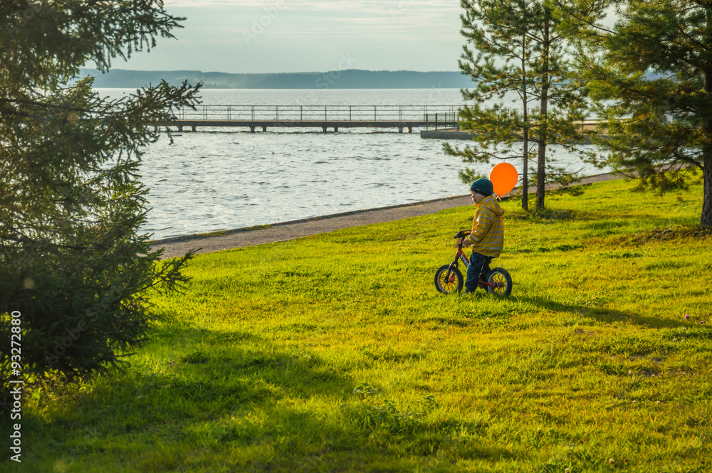 ребёнок на велосипеде стоит на траве рядом с рекой