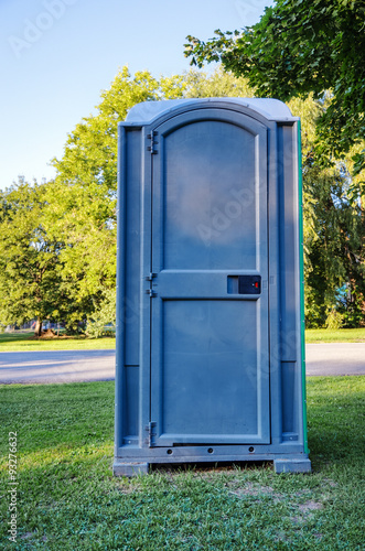 Siingle Blue Outhouse on Grass in Park photo