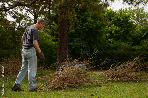 Man doing yardwork, cutting twig brances and tying into bundles.