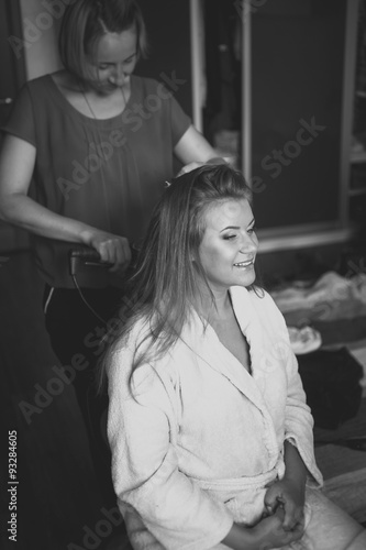 portrait of hairstylist preparing happy bride to wedding ceremon