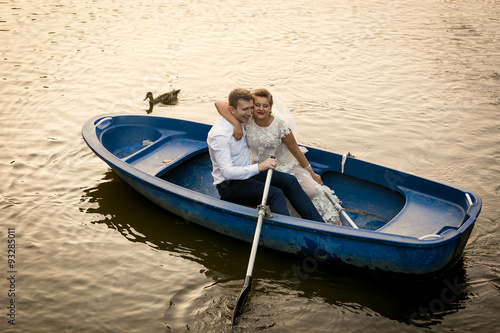 Smiling bride and groom embracing on the rowing boat © Кирилл Рыжов