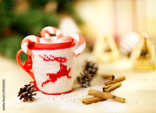 Picture of Christmastime gingerbread with cup of coffee on wooden table  New Year sweets still life on dark glowing brown background  little decorative Christmas tree  candy cane