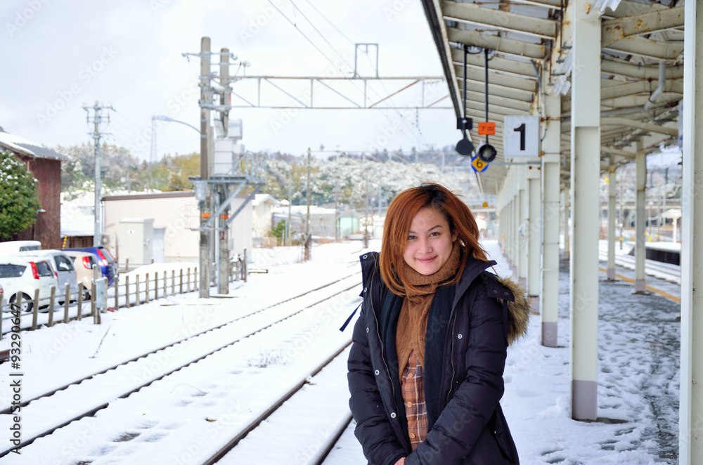 雪化粧した駅と若い女性