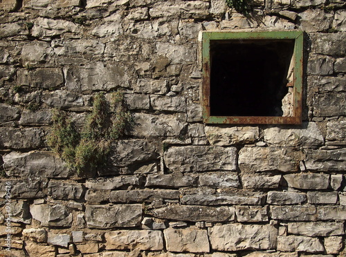 Old stone wall with a broken windows.