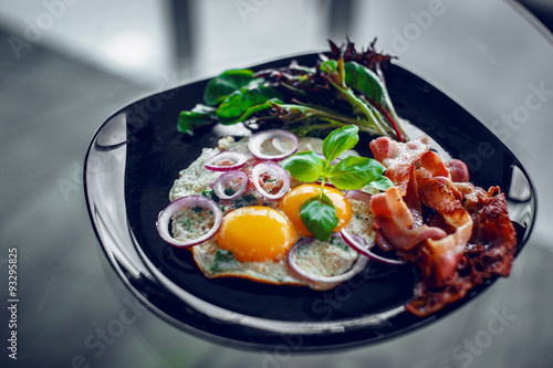 Cooked eggs with vegetables on black plate.