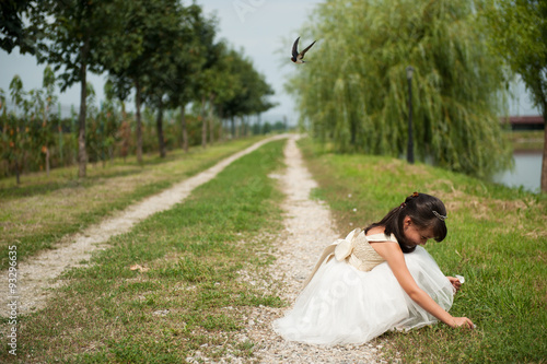 girl picking flowers by the village road on her flying bird