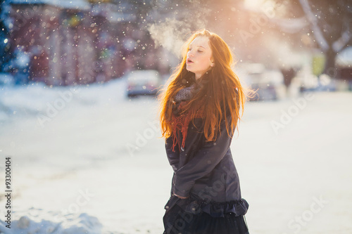 Positive redhead girl on the sun in frozen winter day