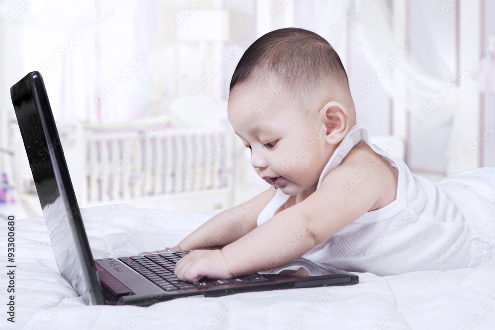 Curious male baby playing notebook computer Curious male baby playing notebook computer