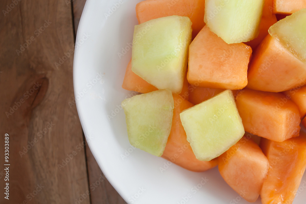 closeup melon slice in white dish with wood table background closeup melon slice in white dish with wood table background