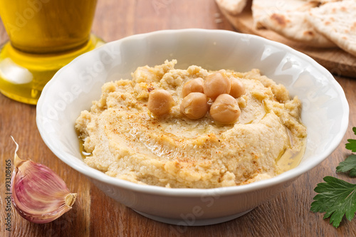 bowl with hummus, ingredients and slices of pita