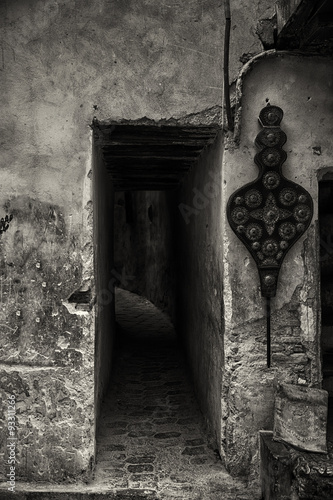 Entrance to dark narrow alley in Fes medina, black and white image.
