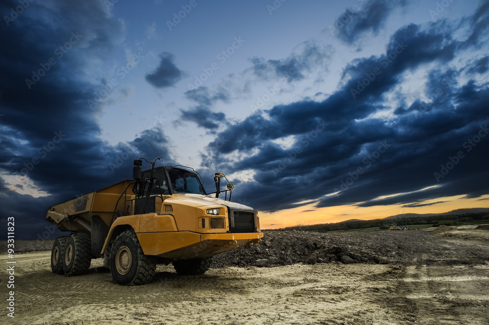 Großer Muldenkipper auf Baustelle mit düsteren Abendwolken Großer Muldenkipper auf Baustelle mit düsteren Abendwolken