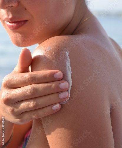 Joven mujer aplicando crema de proteccion solar en la espalda. photo