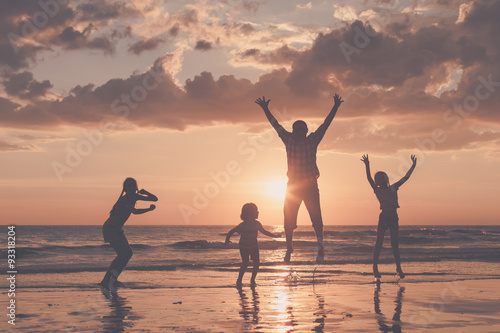 Father and children playing on the beach at the sunset time.