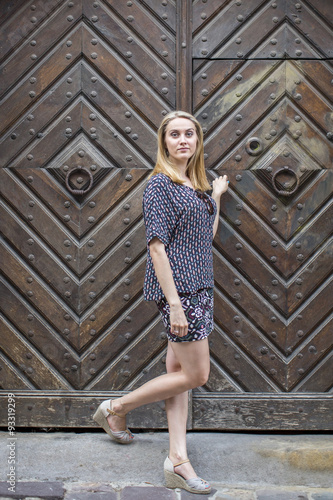 Young woman stands in front of an ancient door.