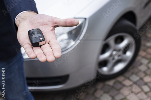 man hand with car in background holding a automobile key