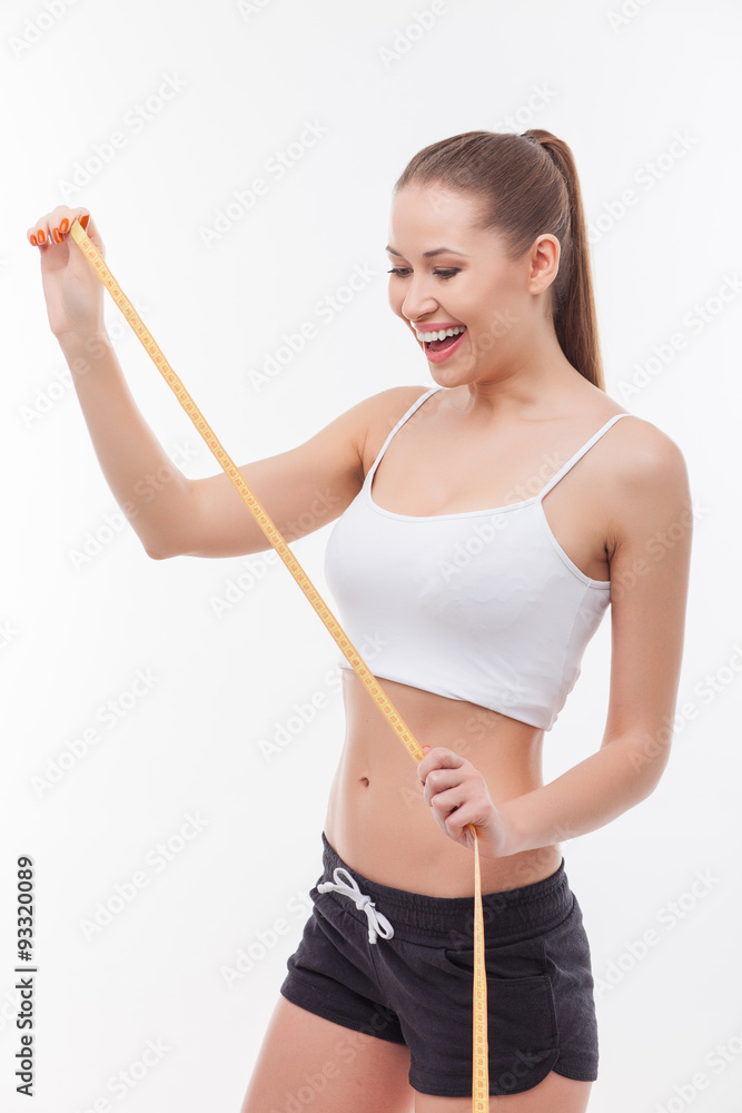 Cheerful young slim girl is taking measurement of her body Cheerful young slim girl is taking measurement of her body