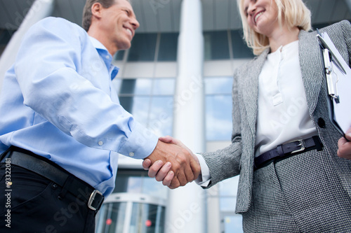 Skillful colleagues are greeting each other with handshake