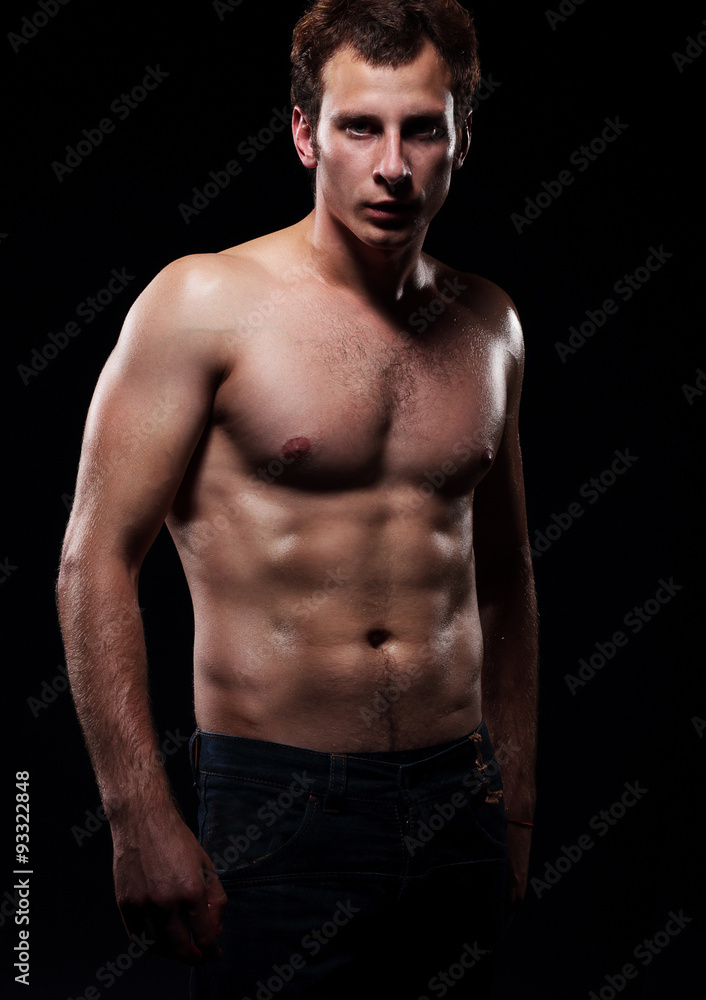 Body of a young muscular man, studio dark background. Body of a young muscular man, studio dark background.