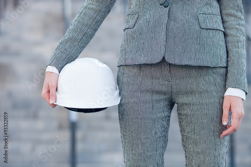 Cheerful female engineer with hardhat in arm