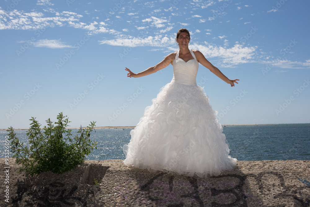 Naklejka premium A married woman bride in her wedding dress in sunshine on a beautiful tropical beach