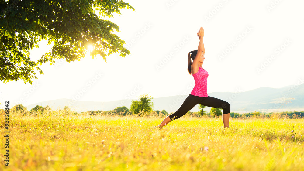 Young athletic woman practicing yoga on a meadow at sunset, image with lens flare Young athletic woman practicing yoga on a meadow at sunset, image with lens flare