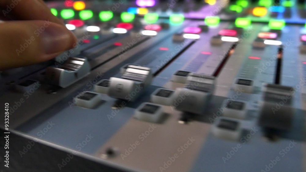 A moving shot of an audio mixer and a man pulling up the knobs on it, the shot is moving from the left to the right... A moving shot of an audio mixer and a man pulling up the knobs on it, the shot is moving from the left to the right...