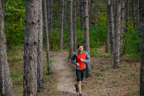 Young Man Running on the Trail in the Wild Pine Forest. Active Lifestyle