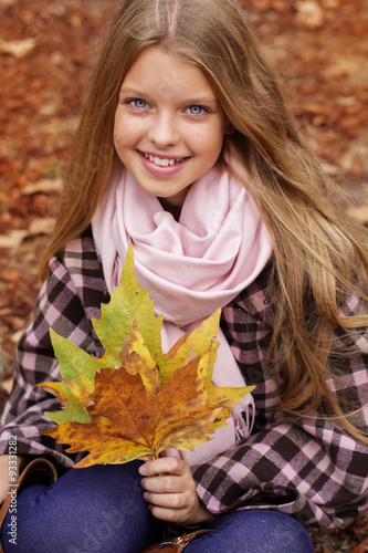 Cute smiling girl with maple leaves in hands