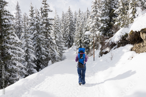 Mother walking in the snow with baby on her back