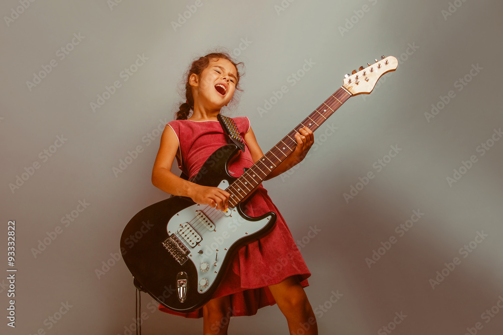 Girl European appearance ten years playing guitar on a blue bac Girl European appearance ten years playing guitar on a blue bac