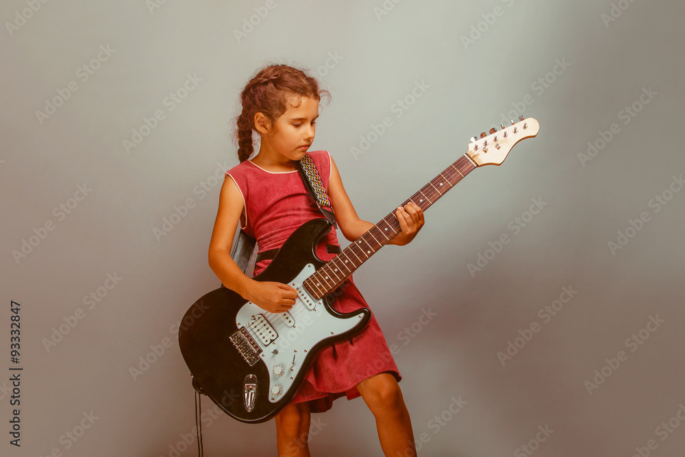 Girl European appearance ten years playing guitar on a blue back Girl European appearance ten years playing guitar on a blue back