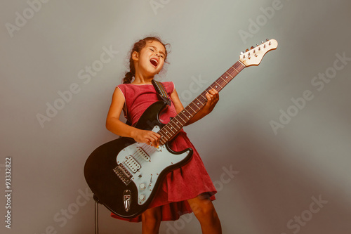 Girl European appearance ten years playing guitar on a blue bac