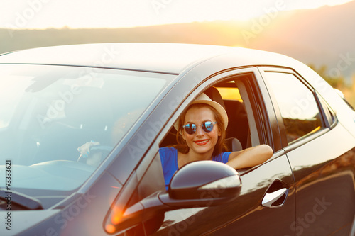 Smiling woman driving a car at sunset